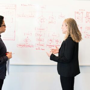 Two professionals brainstorming digital marketing ideas on a whiteboard.